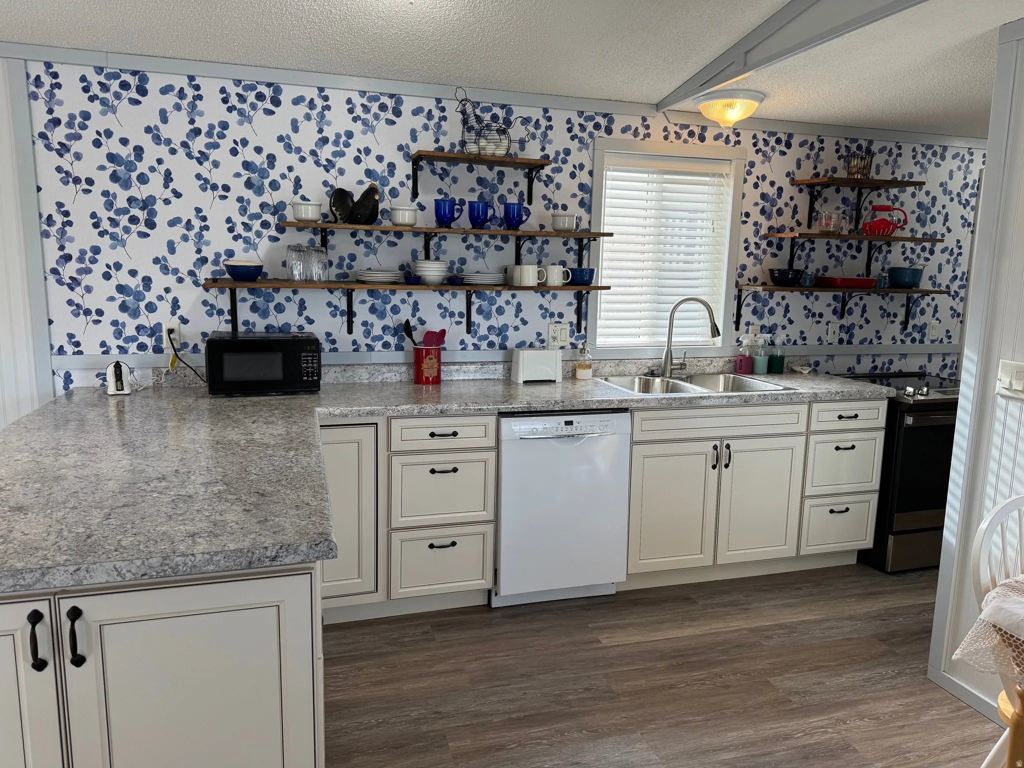 Kitchen with dishwasher, a textured ceiling, electric range, dark wood-type flooring, and light countertops