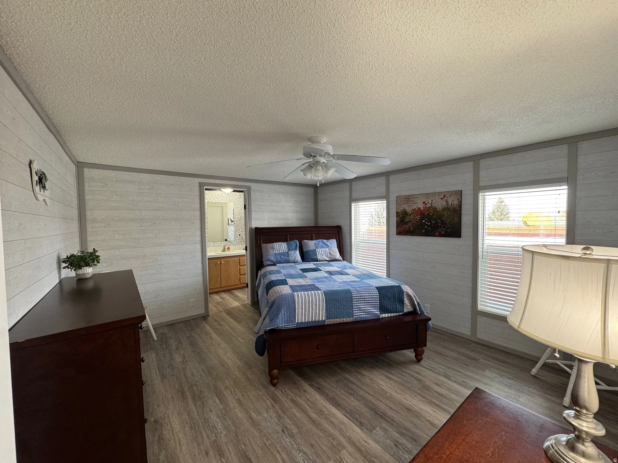 Bedroom with dark wood-type flooring, a textured ceiling, and a ceiling fan