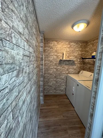 Laundry room featuring a textured ceiling, dark wood-style floors, and washer and dryer