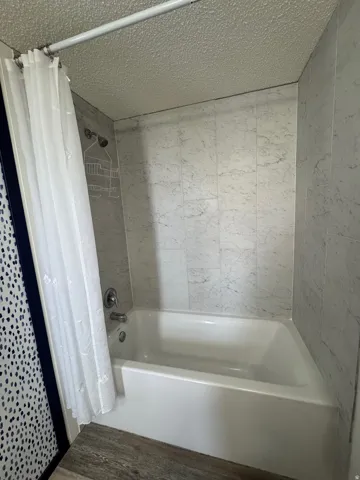 Full bath with a textured ceiling and shower / tub combo