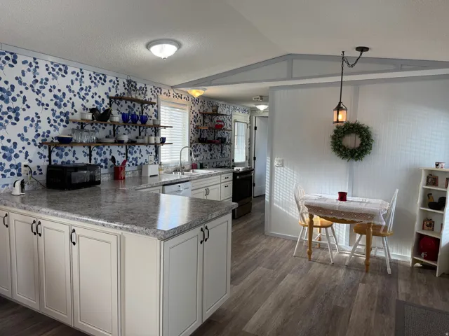 Kitchen with open shelves, a peninsula, dark wood finished floors, stainless steel appliances, and decorative light fixtures
