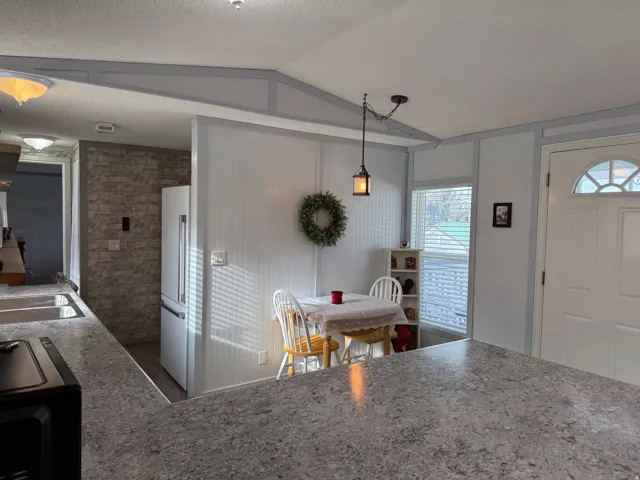 Kitchen with a textured ceiling, high end white fridge, black range oven, and decorative light fixtures