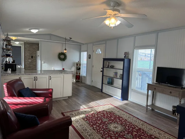 Living room featuring dark wood-style flooring, healthy amount of natural light, ceiling fan, and a textured ceiling