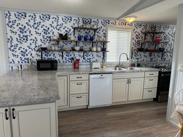 Kitchen with dishwasher, a textured ceiling, electric range, dark wood-type flooring, and light countertops