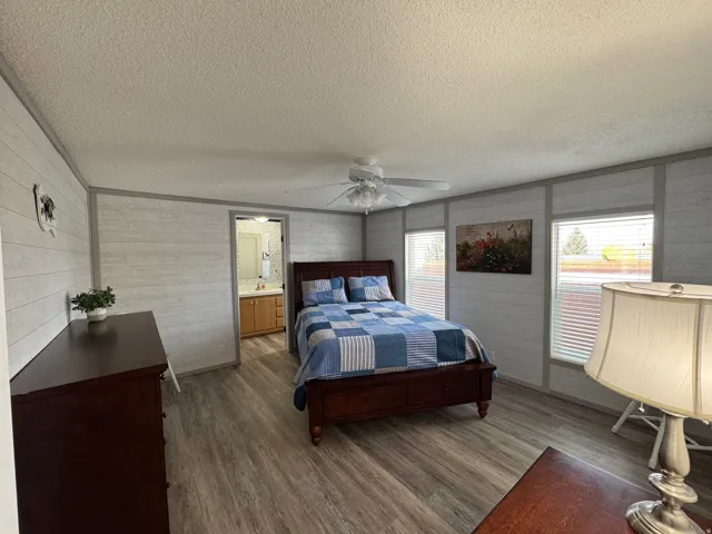 Bedroom with dark wood-type flooring, a textured ceiling, and a ceiling fan