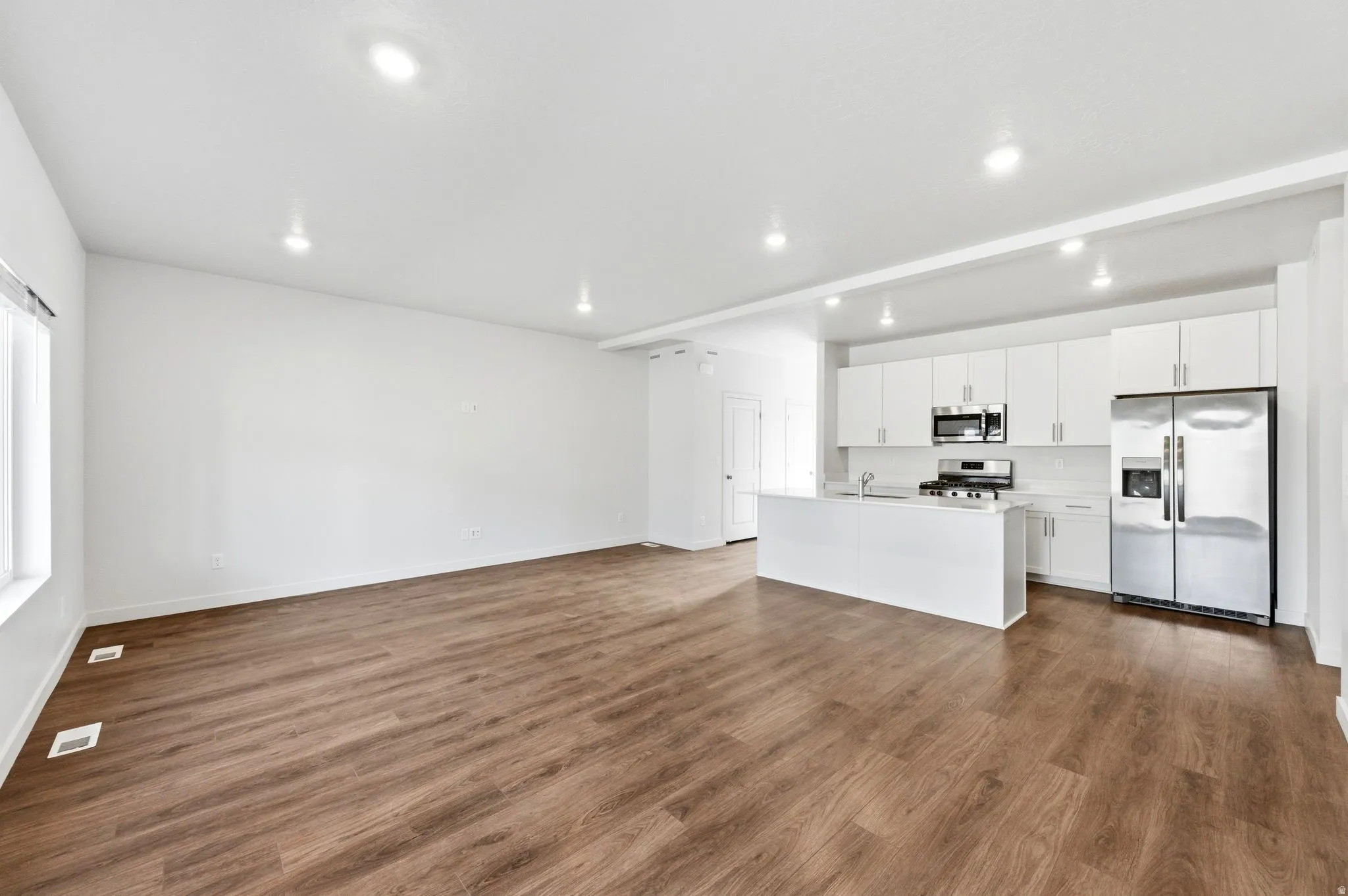 Unfurnished living room with dark wood-type flooring and recessed lighting
