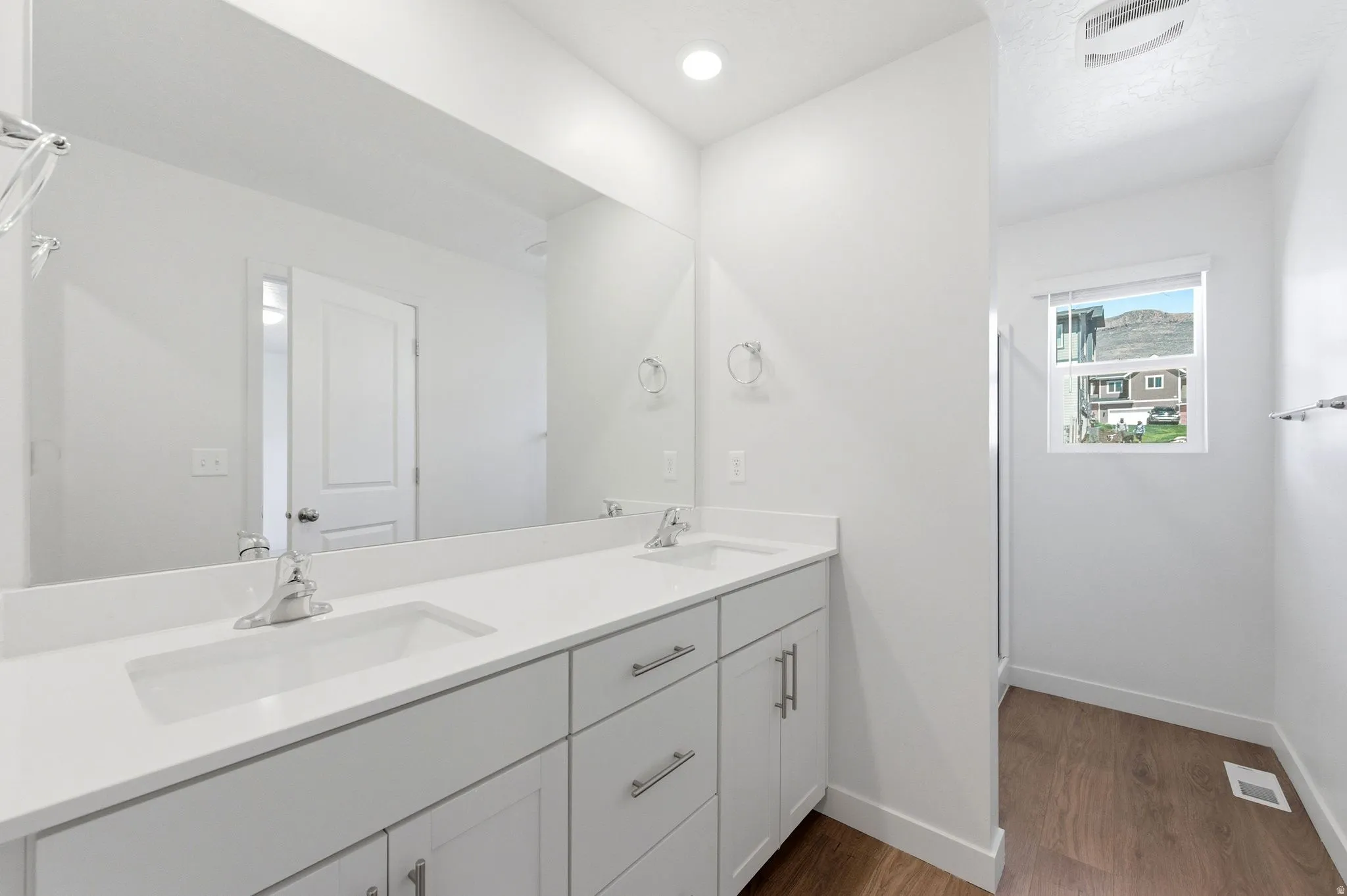Full bath with double vanity, dark wood finished floors, and recessed lighting