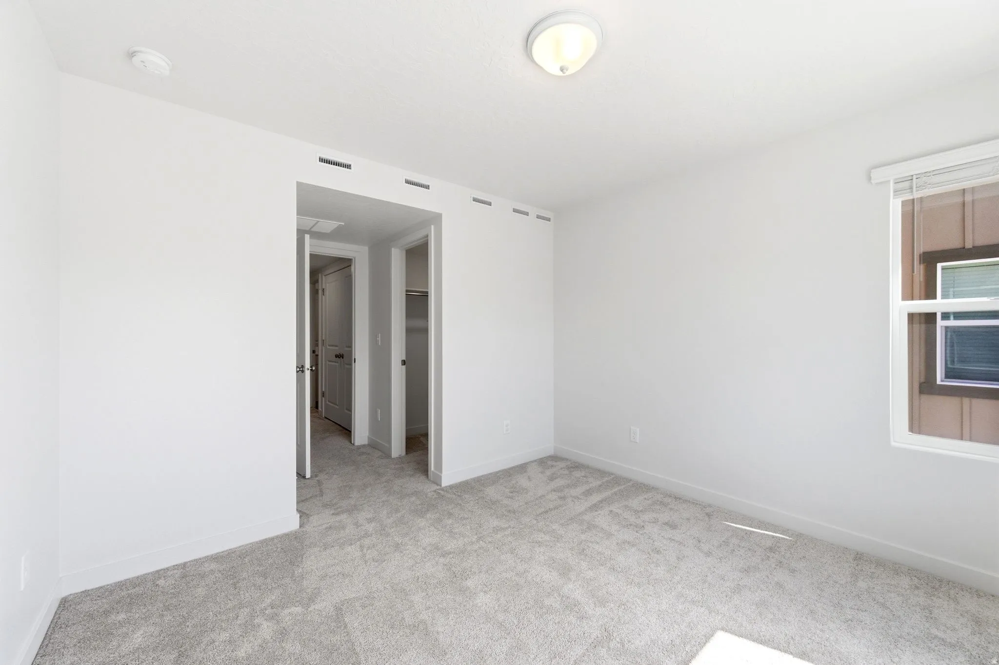 Empty room featuring light carpet and a smoke detector
