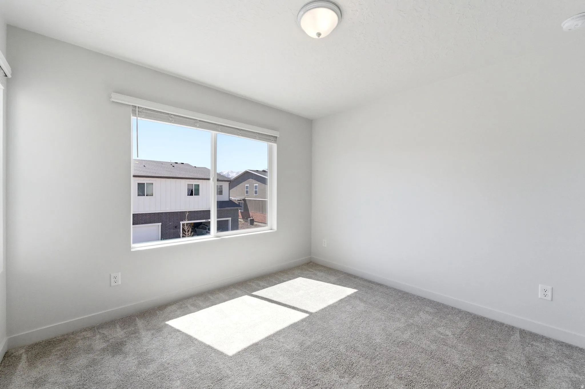 Empty room featuring light carpet and a smoke detector