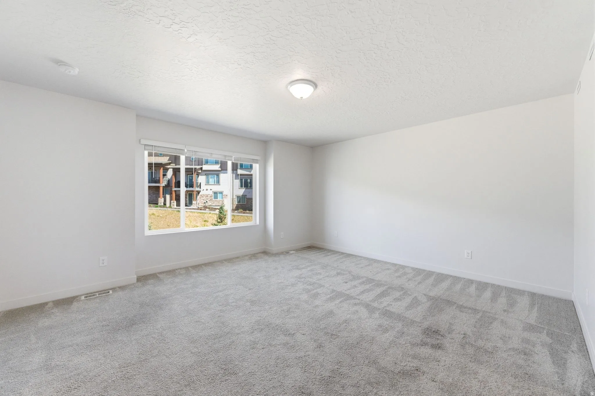 Unfurnished room with light carpet and a textured ceiling