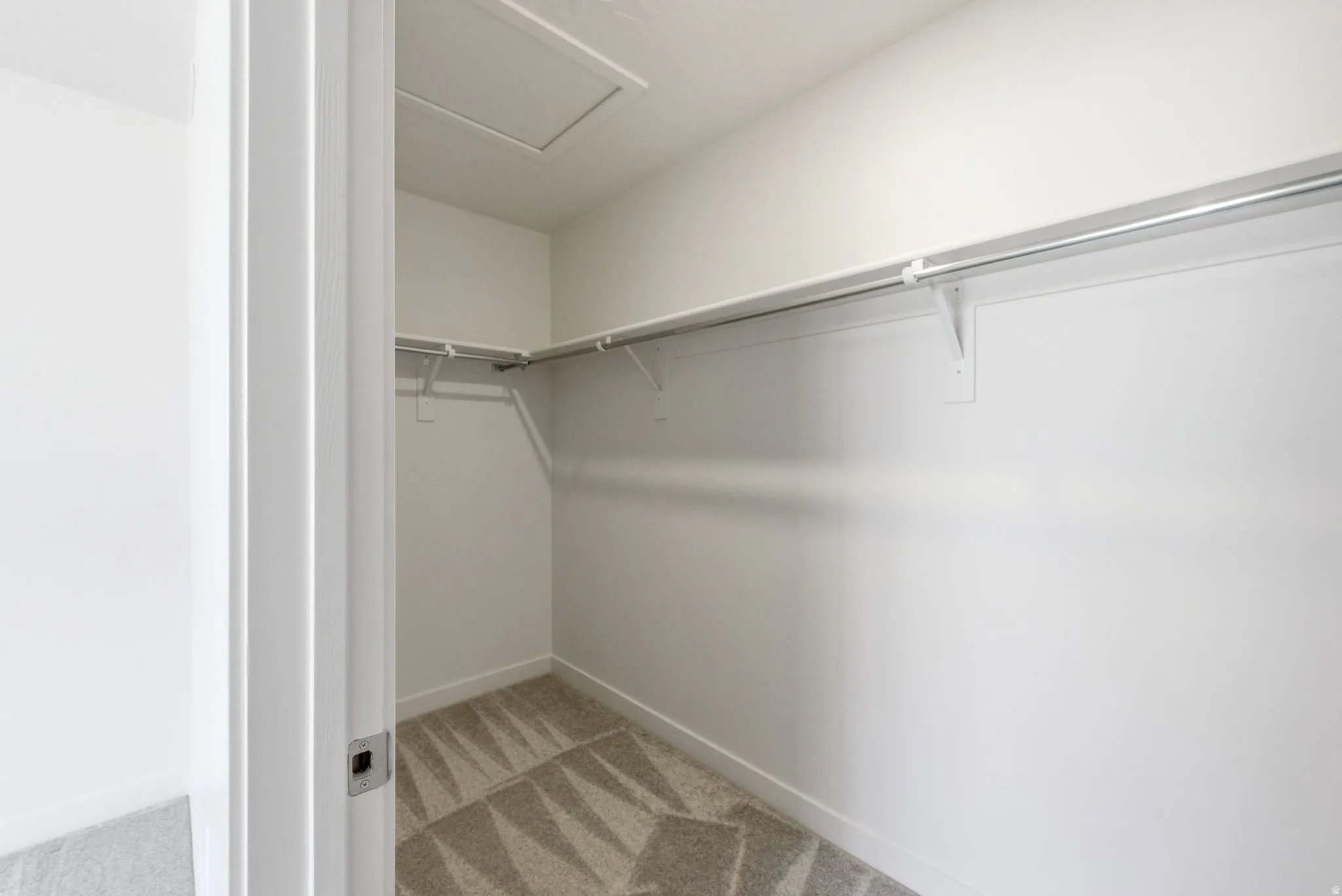 Walk in closet featuring attic access and light carpet