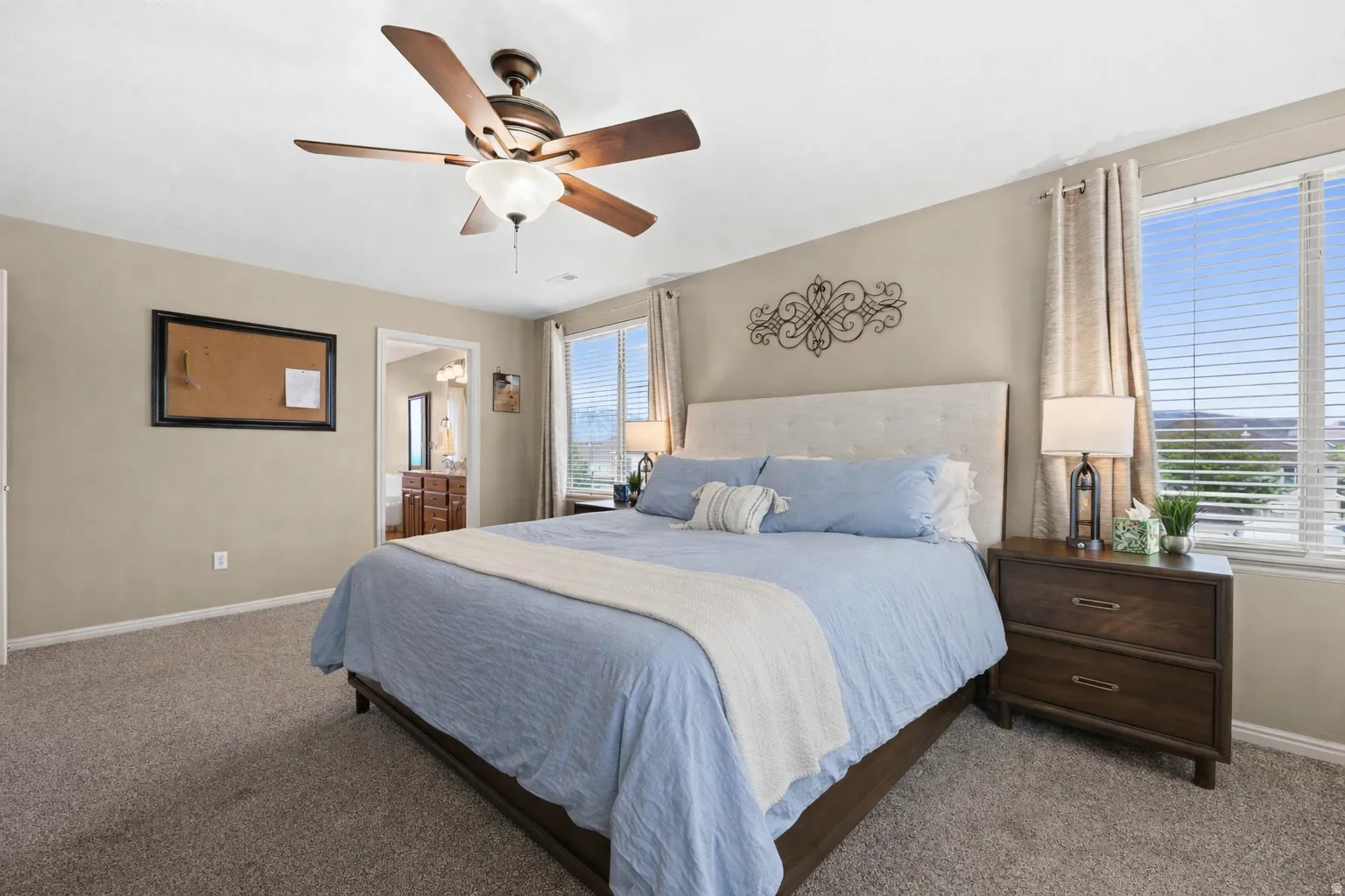 Carpeted bedroom with a ceiling fan and ensuite bath