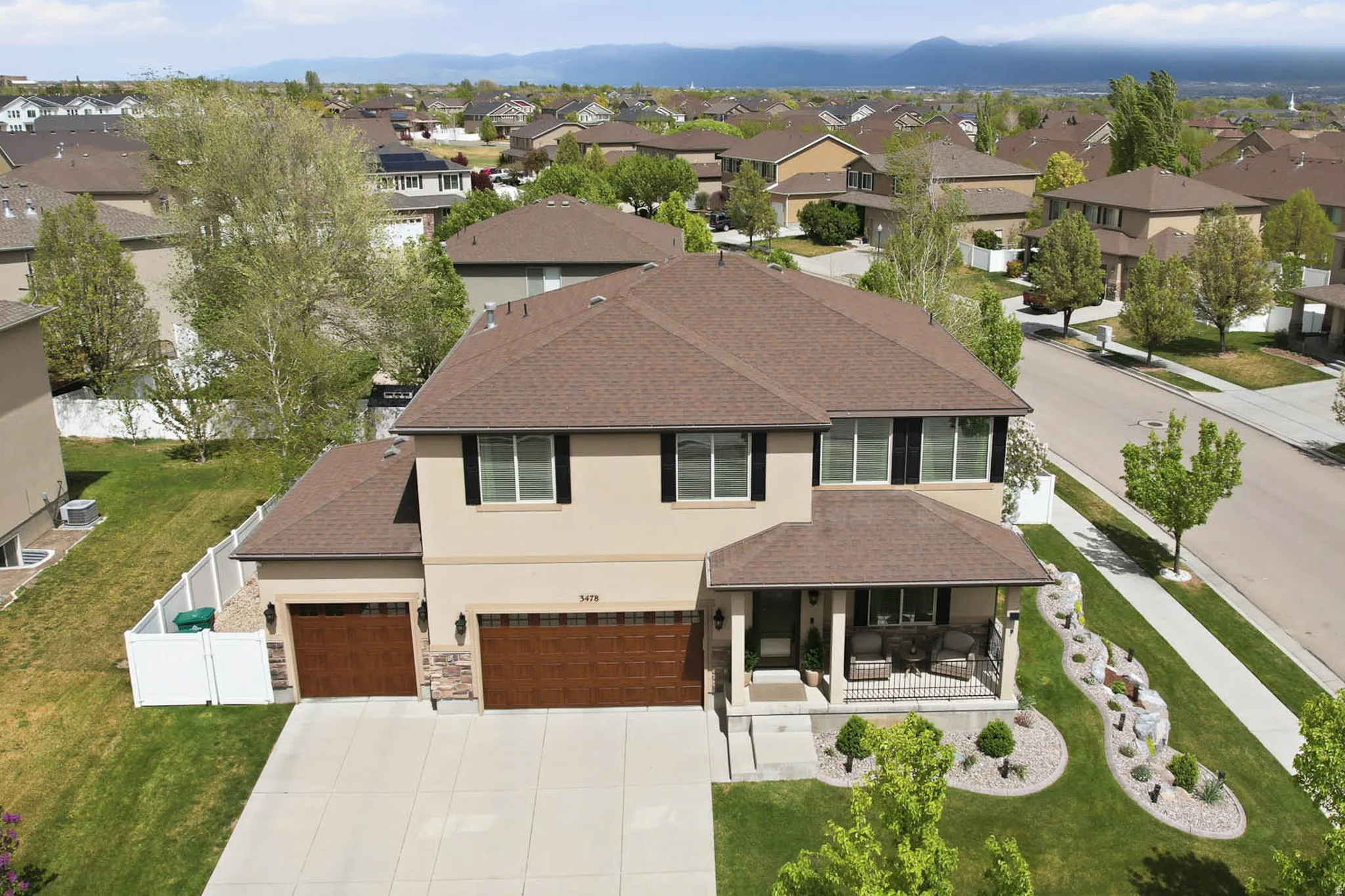 Contemporary residence featuring a covered front porch, a two-car garage with wood-finish doors, and a decorative rock garden