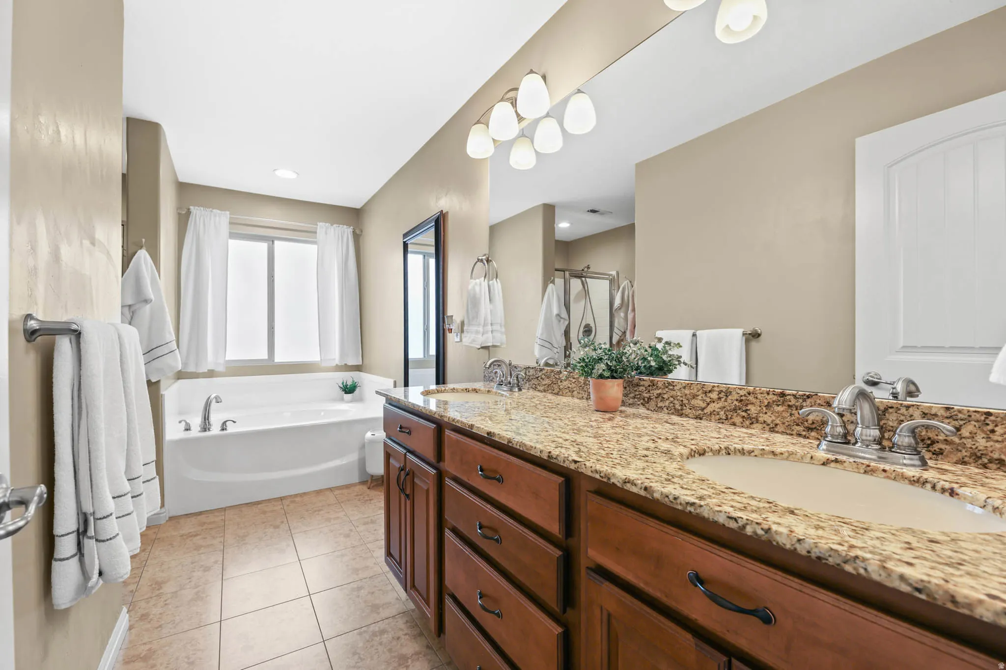 Bathroom with a bath, double vanity, light tile patterned floors, a stall shower, and recessed lighting