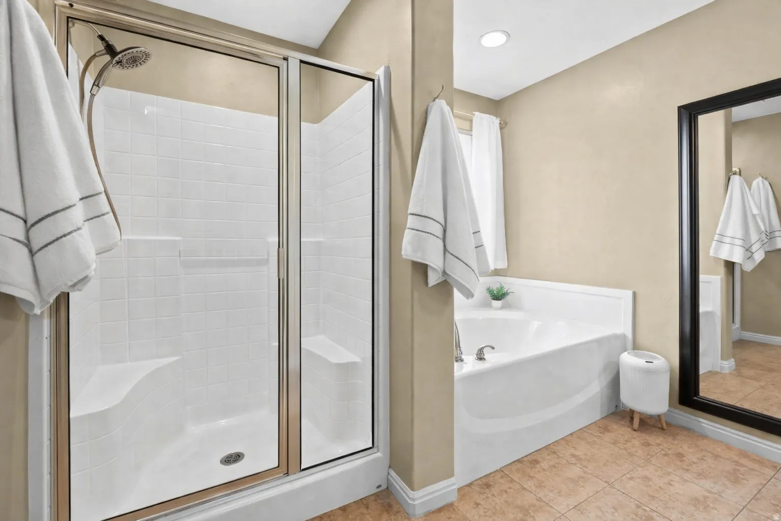 Full bath with a shower stall, a bath tub, and light tile floors
