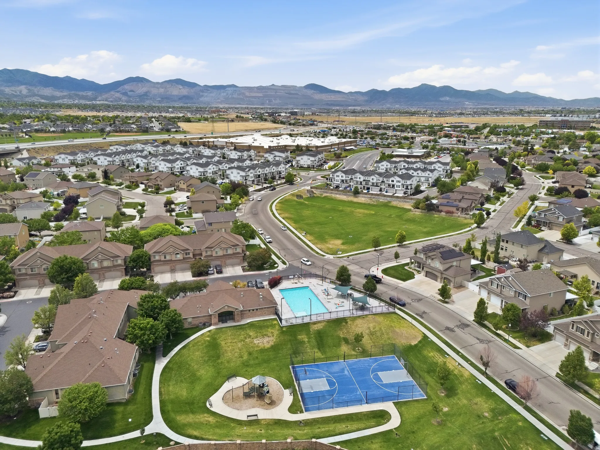 Expansive community featuring a large swimming pool, basketball court, and playground