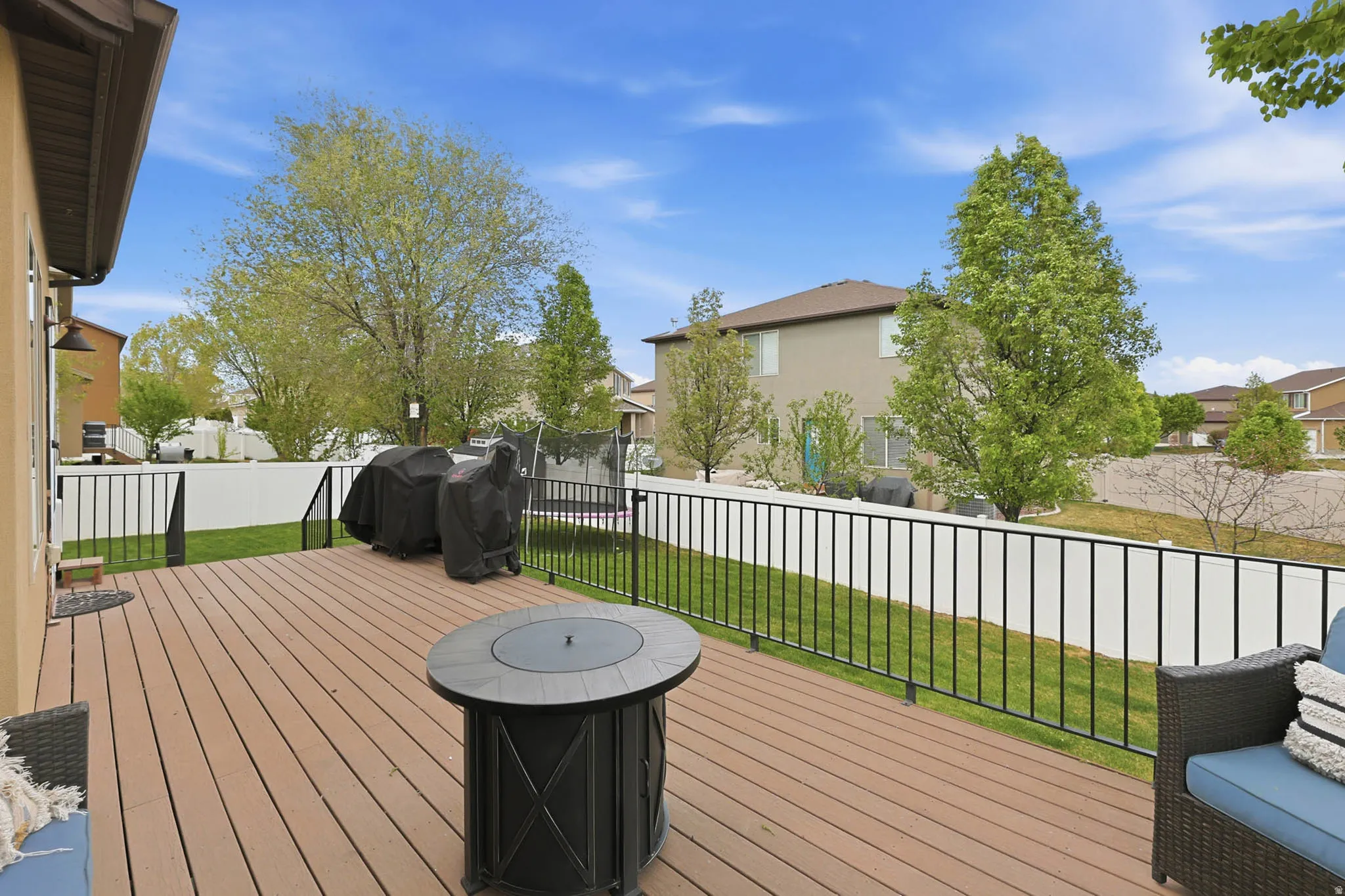 Wooden deck with a residential view, a fenced backyard, and a trampoline