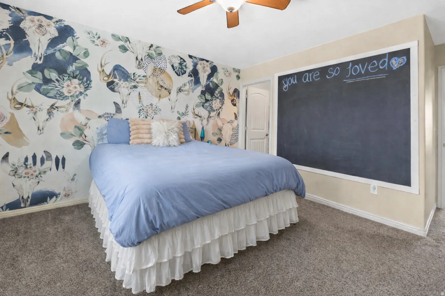 Carpeted bedroom featuring wallpapered walls and a ceiling fan