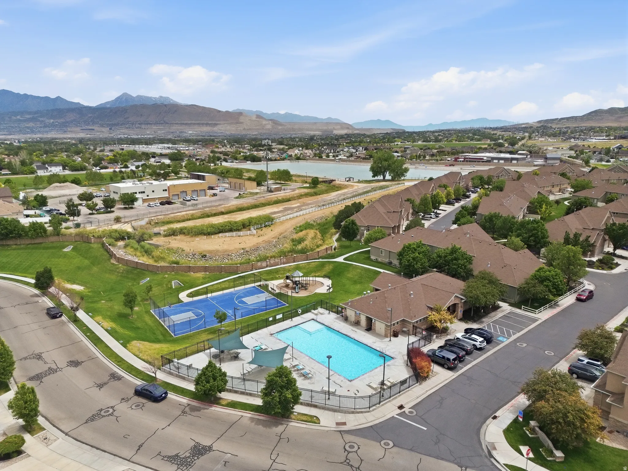 Community amenities including a swimming pool, shaded lounge areas, and sports courts