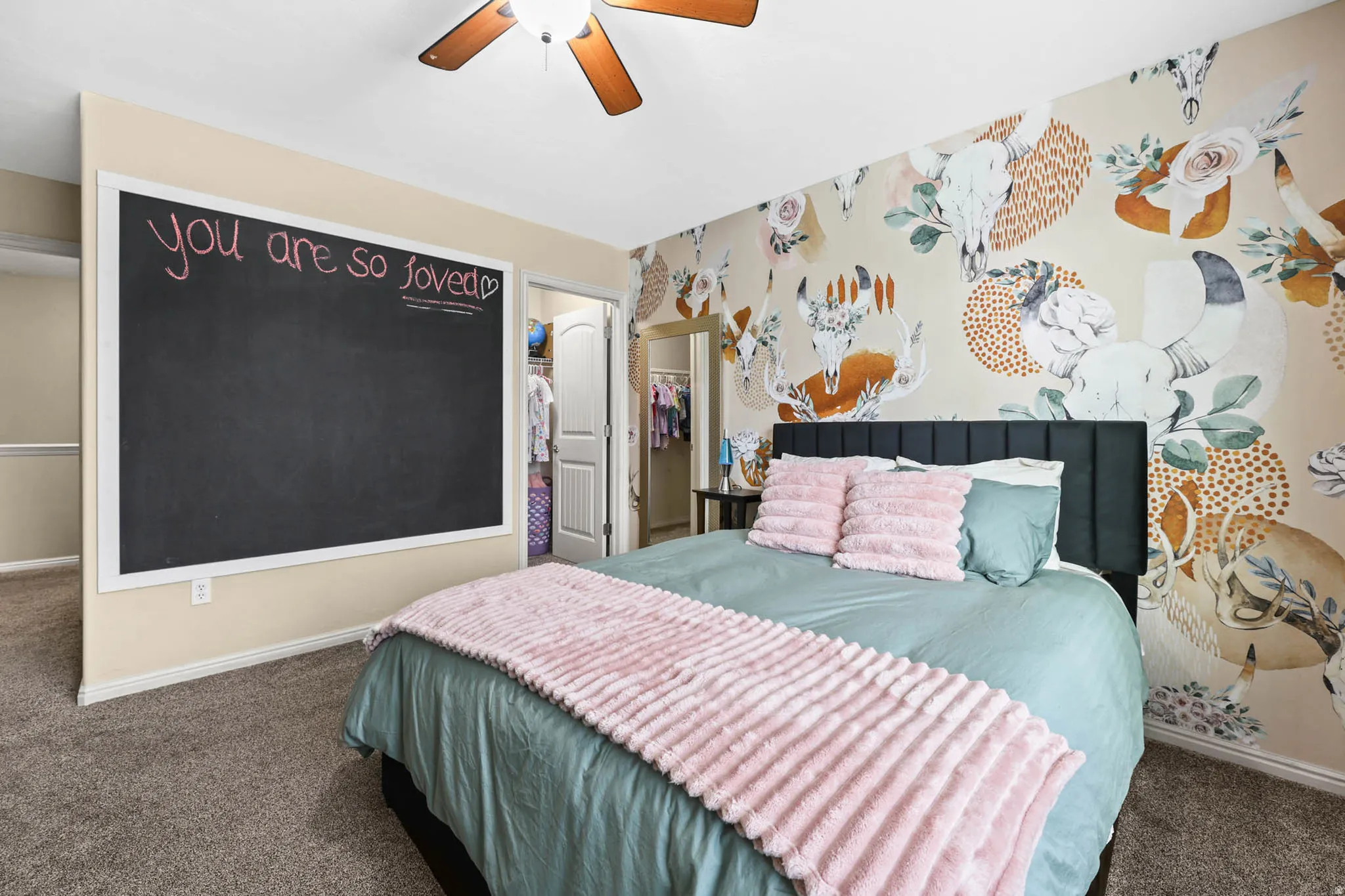 Carpeted bedroom with a walk in closet and a ceiling fan
