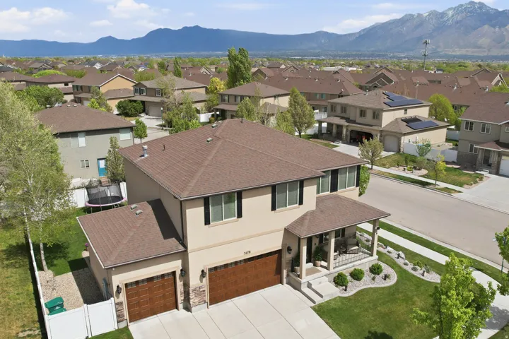 Two-story residence featuring a covered front porch, dual garage doors with a wood-finish, and stone accent siding