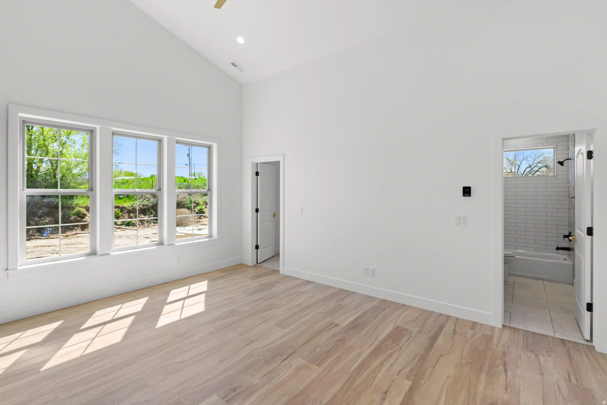 Spare room featuring light wood finished floors, vaulted ceiling, ceiling fan, and recessed lighting