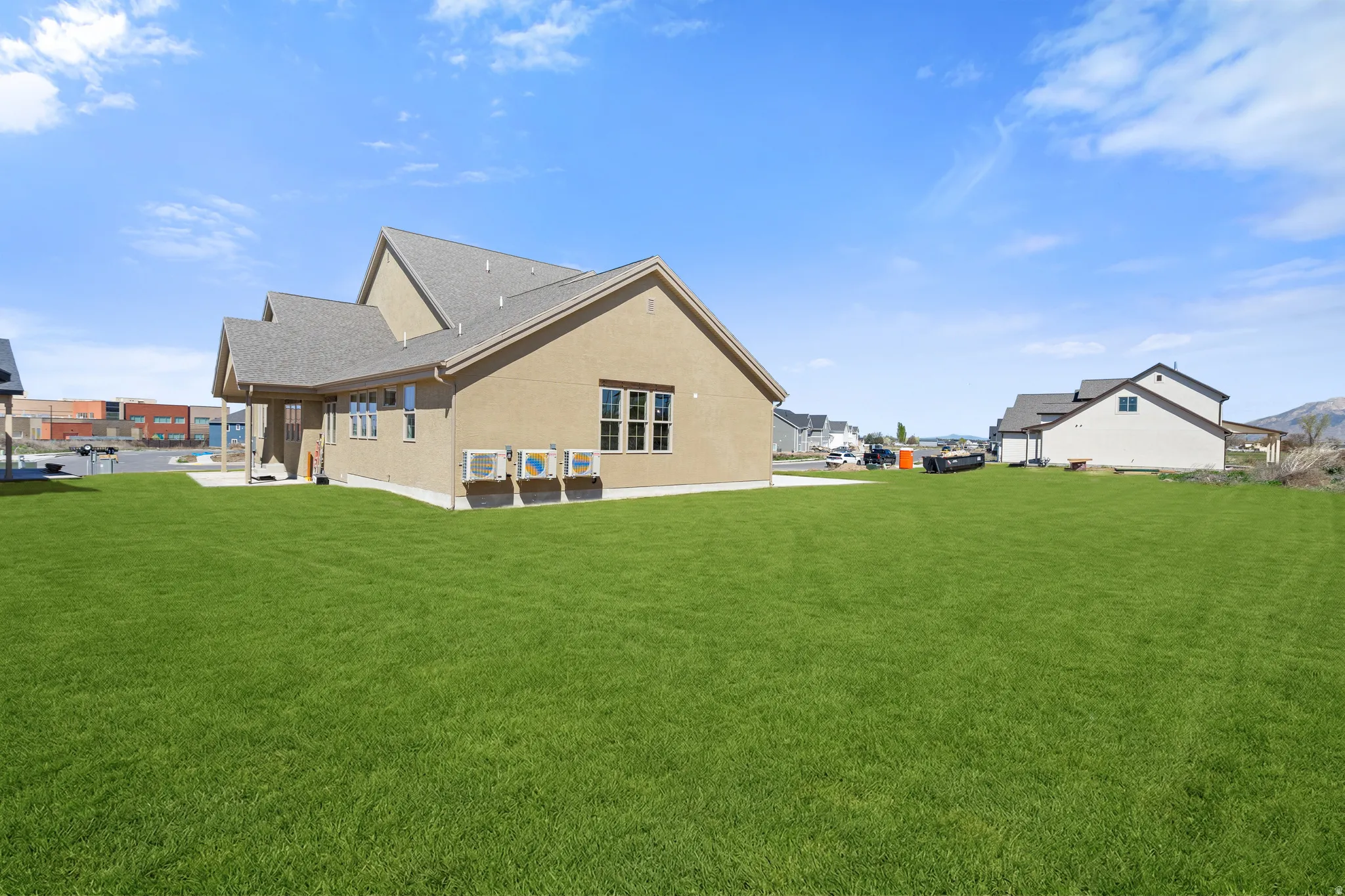 Rear view of house featuring a yard, stucco siding, and roof with shingles