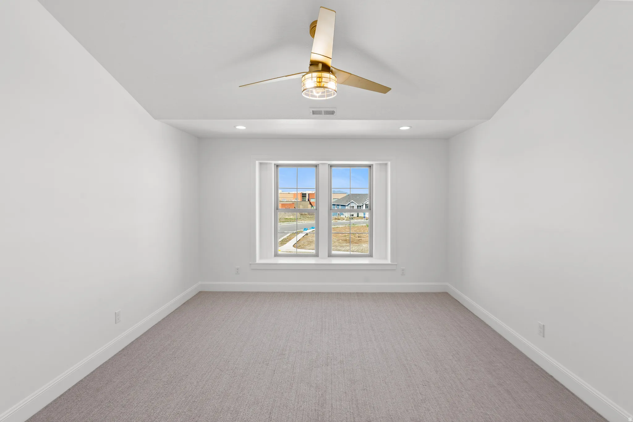Carpeted spare room with a ceiling fan and baseboards