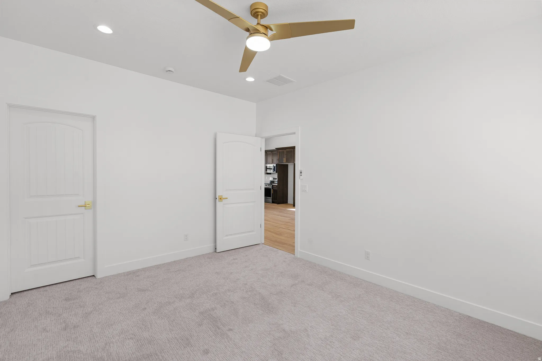 Unfurnished bedroom with light colored carpet, ceiling fan, and recessed lighting