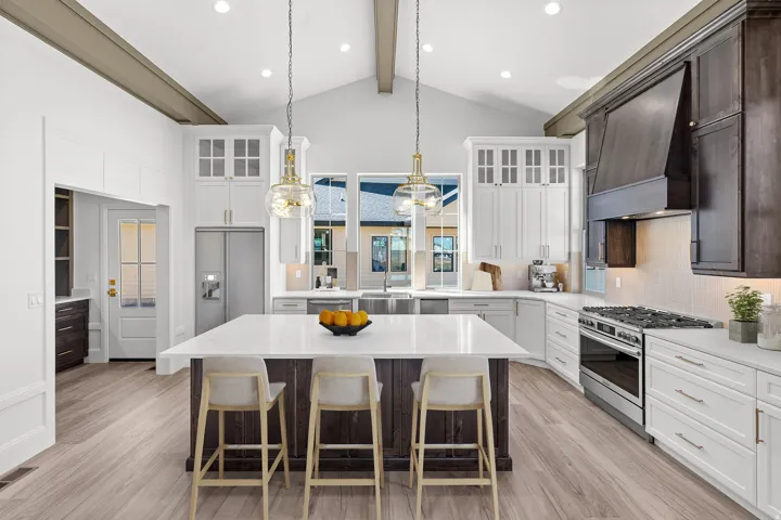 Dual tone kitchen featuring decorative backsplash, stainless steel appliances, a breakfast bar, light wood finished floors, and light stone counters