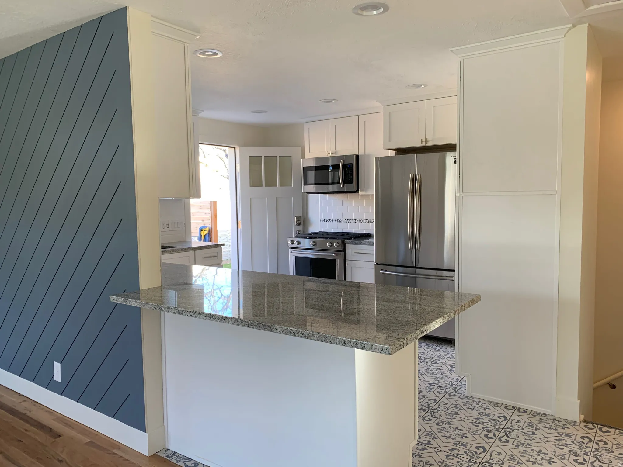 Kitchen featuring dark stone countertops, stainless steel appliances, white cabinetry, a peninsula, and recessed lighting