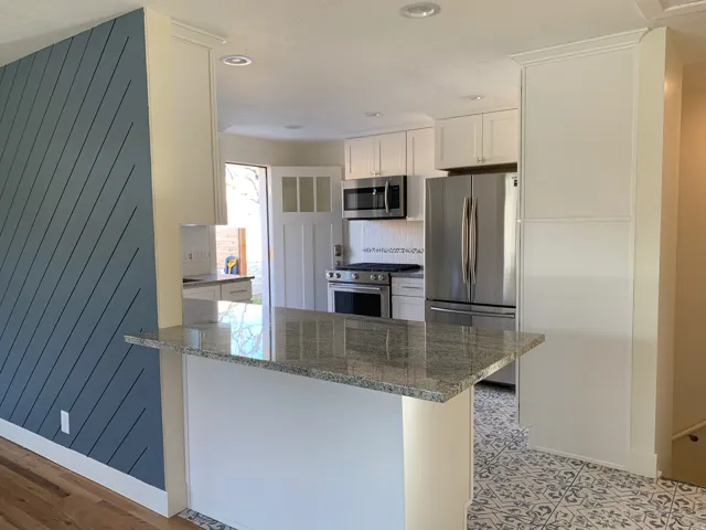 Kitchen featuring dark stone countertops, stainless steel appliances, white cabinetry, a peninsula, and recessed lighting