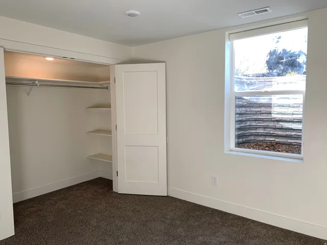Unfurnished bedroom featuring dark carpet and a closet