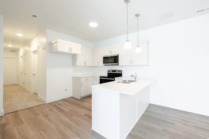 Kitchen featuring white cabinetry, a stainless steel microwave, and an electric range