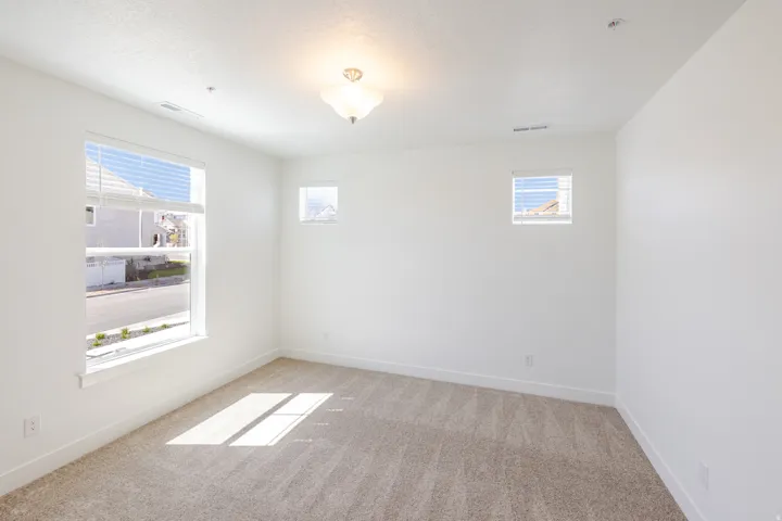 Neutral wall color, carpet flooring, multiple windows, and overhead lighting