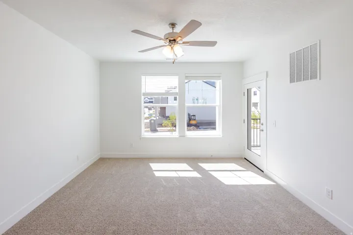 Carpeted flooring, ceiling fan with integrated lighting, window with blinds, and white door with integrated glass panel leading to a balcony