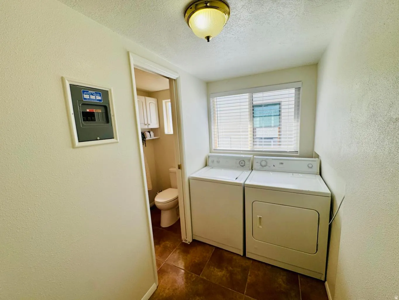 Laundry room featuring a textured wall, independent washer and dryer, and a textured ceiling