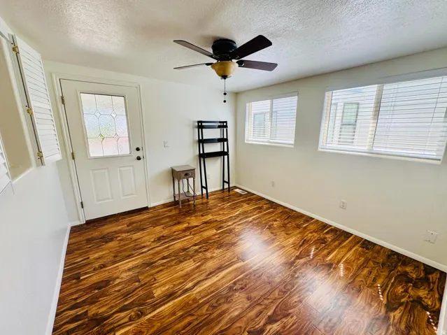 Foyer entrance with dark wood-style flooring, a textured ceiling, and ceiling fan