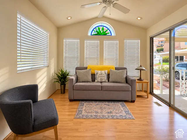 Sunroom featuring vaulted ceilings, wood-finish flooring, recessed lighting, a ceiling fan, and an arched transom window