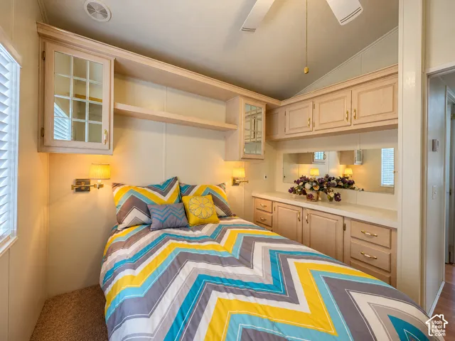 Built-in light-colored cabinetry featuring glass-panel upper doors, integrated wall-mounted task lighting, ceiling fan, and extensive storage surround
