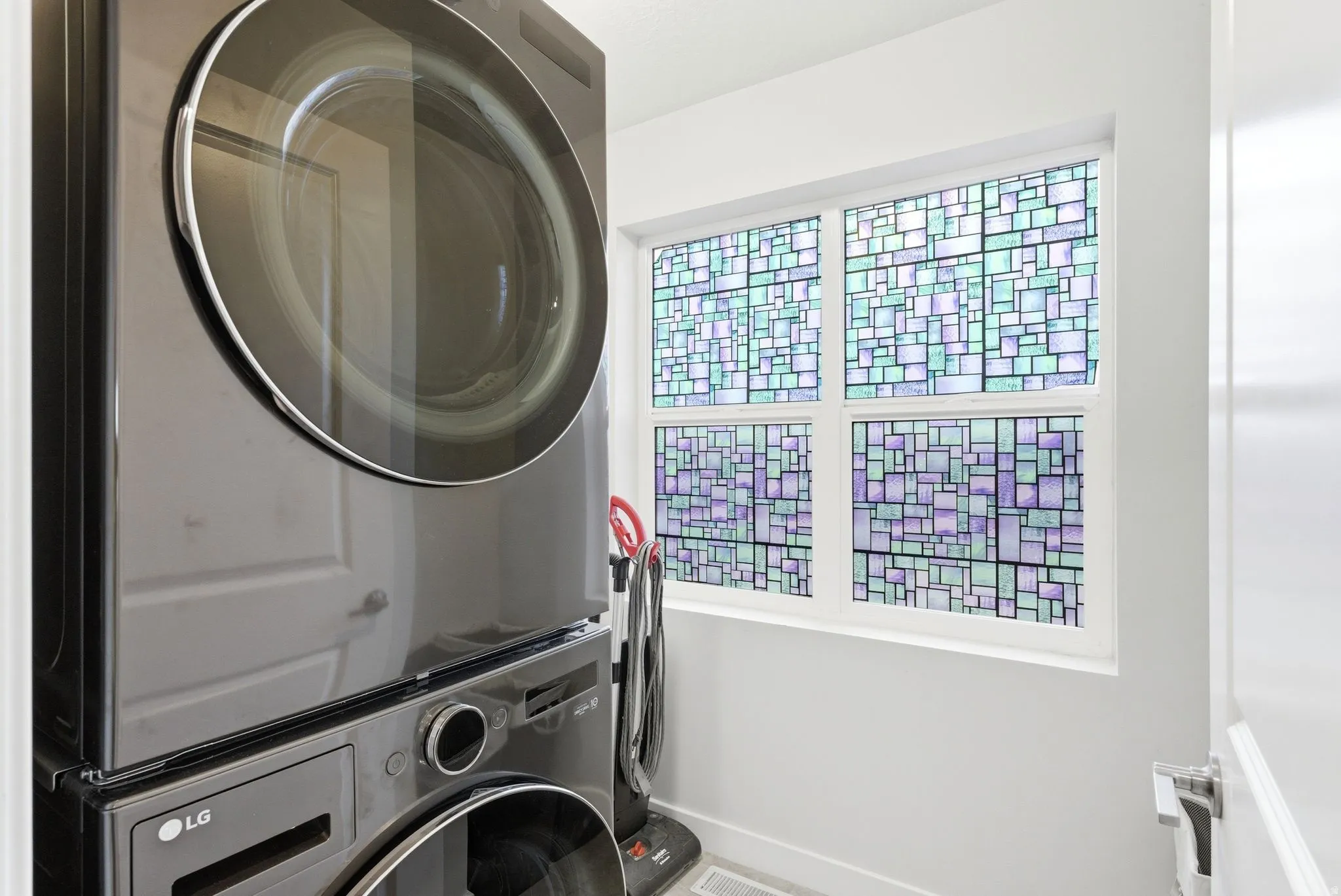 Laundry area featuring stacked washer and dryer and baseboards