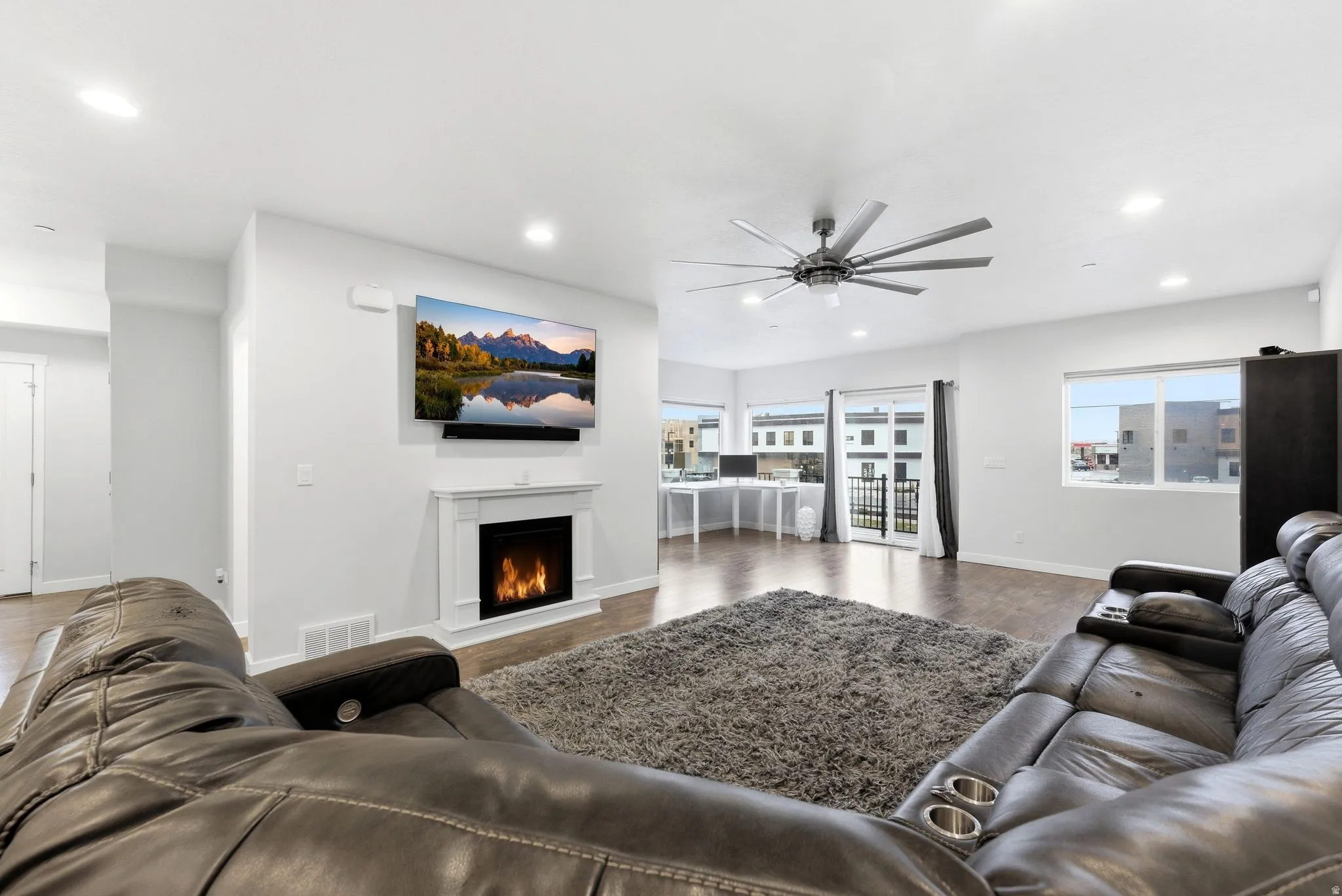 Living area with a lit fireplace, wood finished floors, a ceiling fan, and recessed lighting