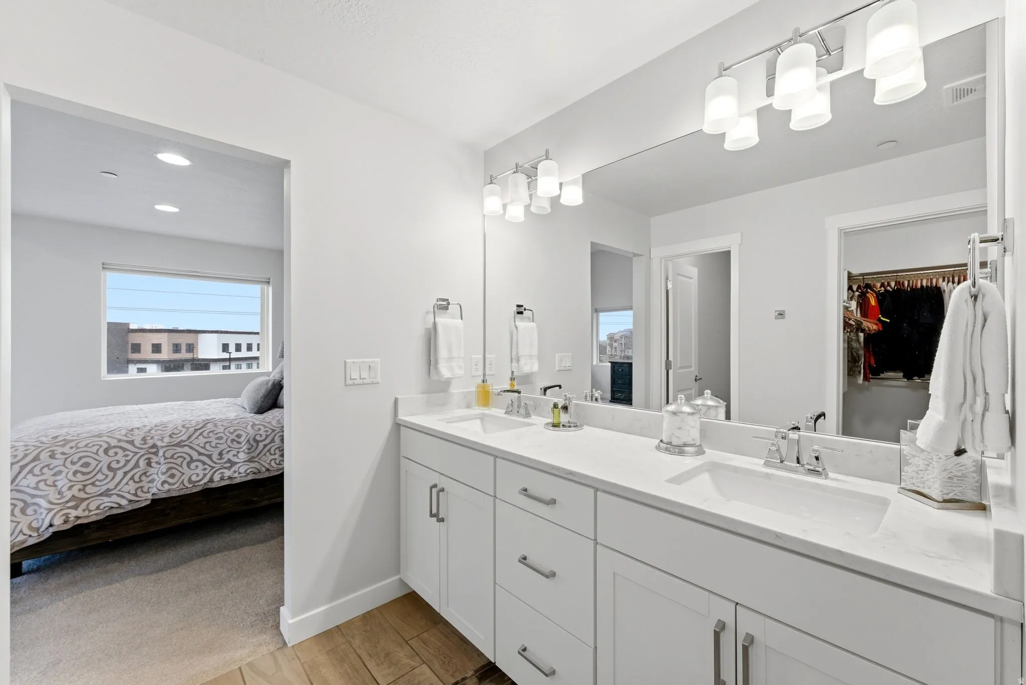 Full bath with double vanity, wood tiled floors, connected bathroom, a spacious closet, and recessed lighting