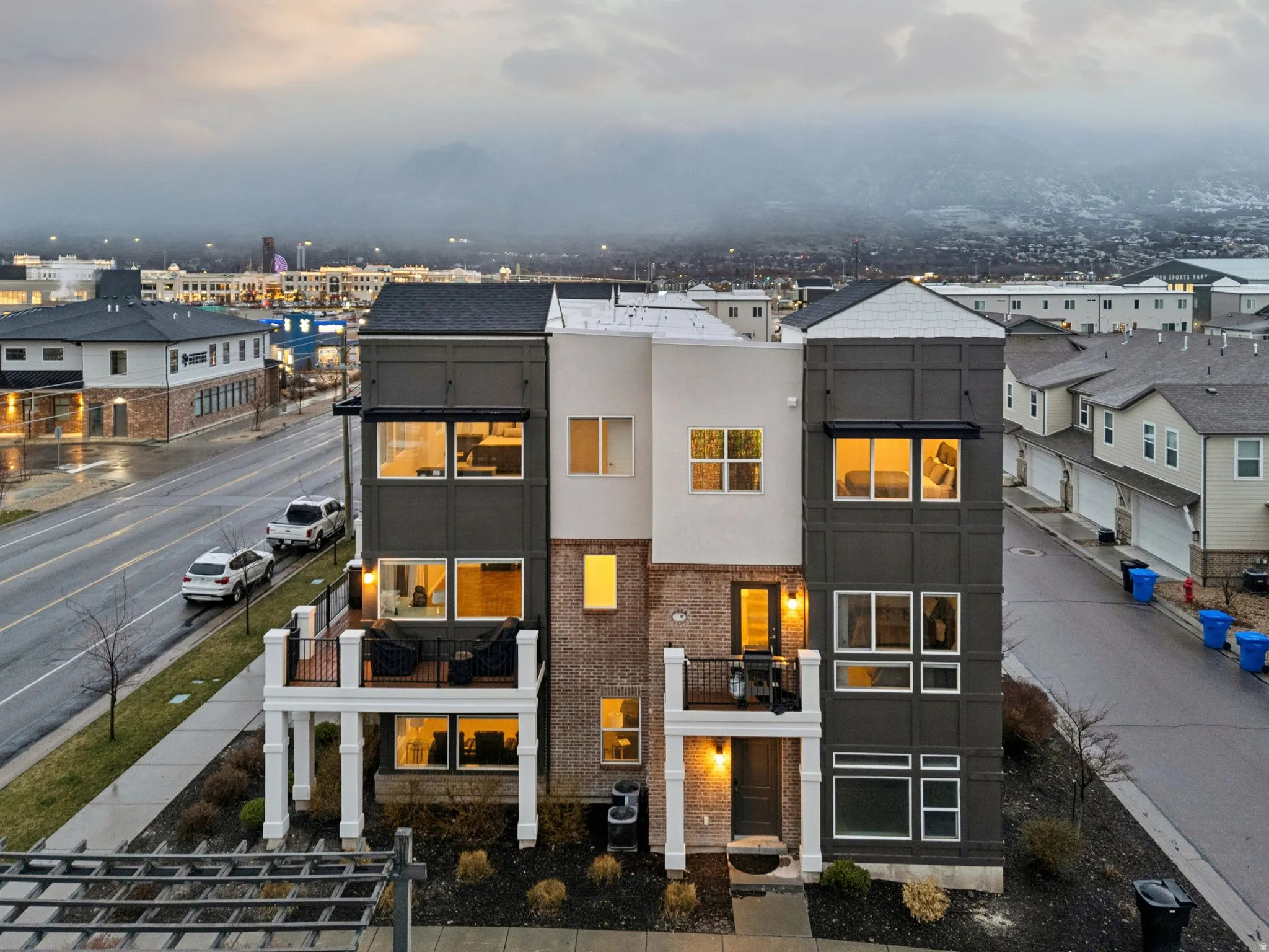 View of front facade with stucco siding, a balcony, and brick siding