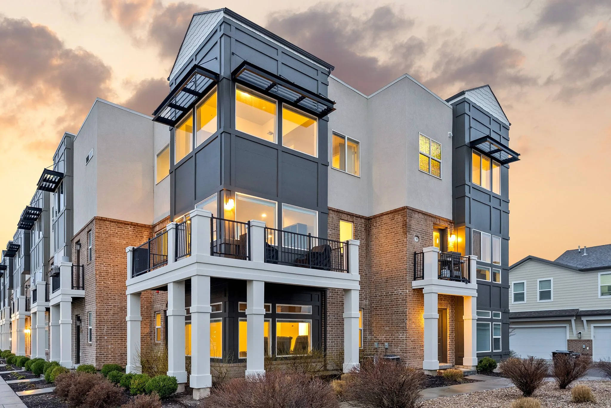 Contemporary house with brick siding, stucco siding, and a balcony