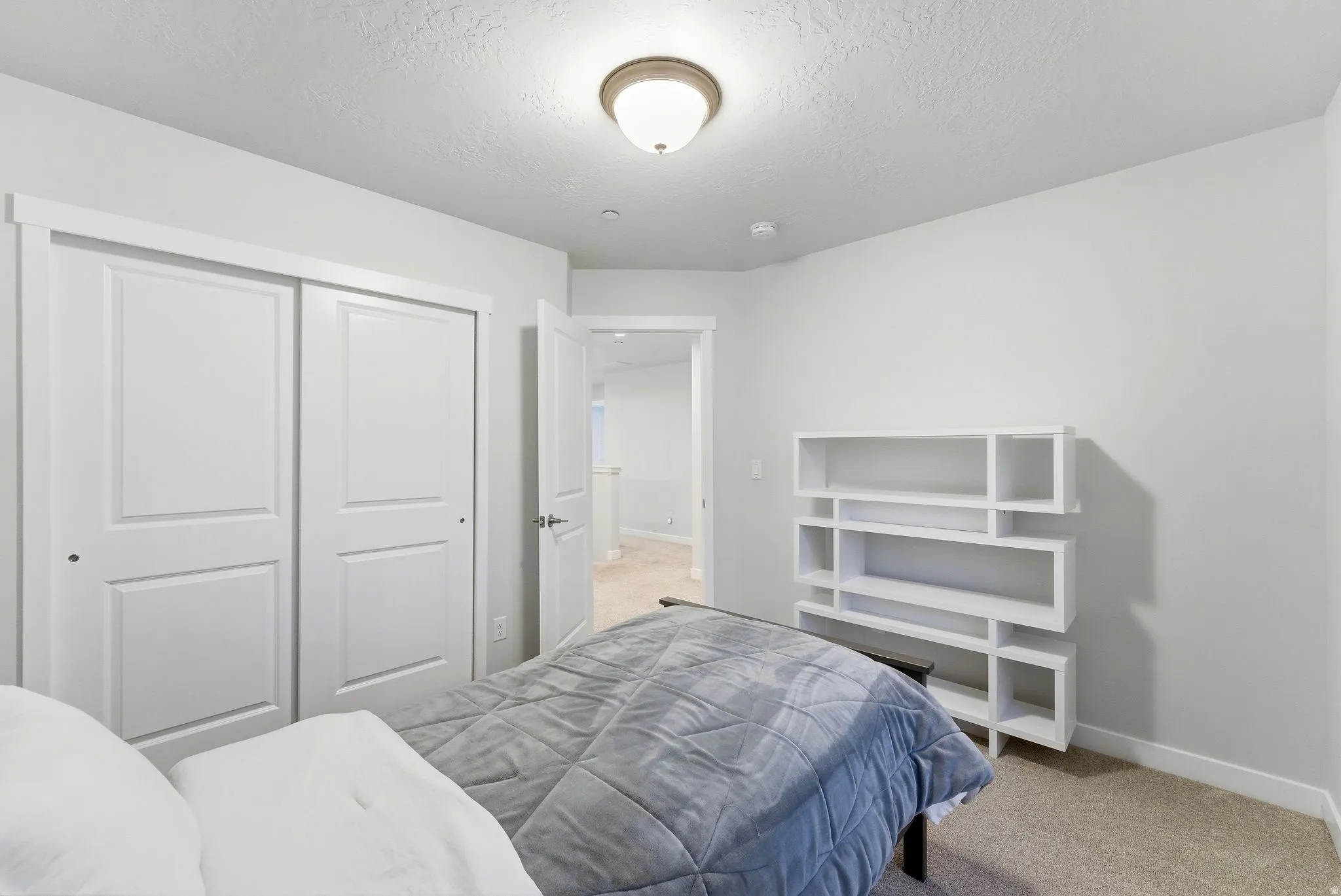 Bedroom featuring light colored carpet, a closet, and a textured ceiling