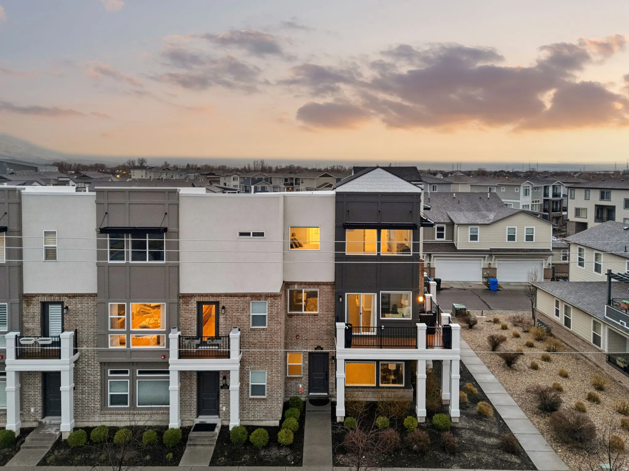 Contemporary house featuring brick siding, a balcony, stucco siding, and a residential view
