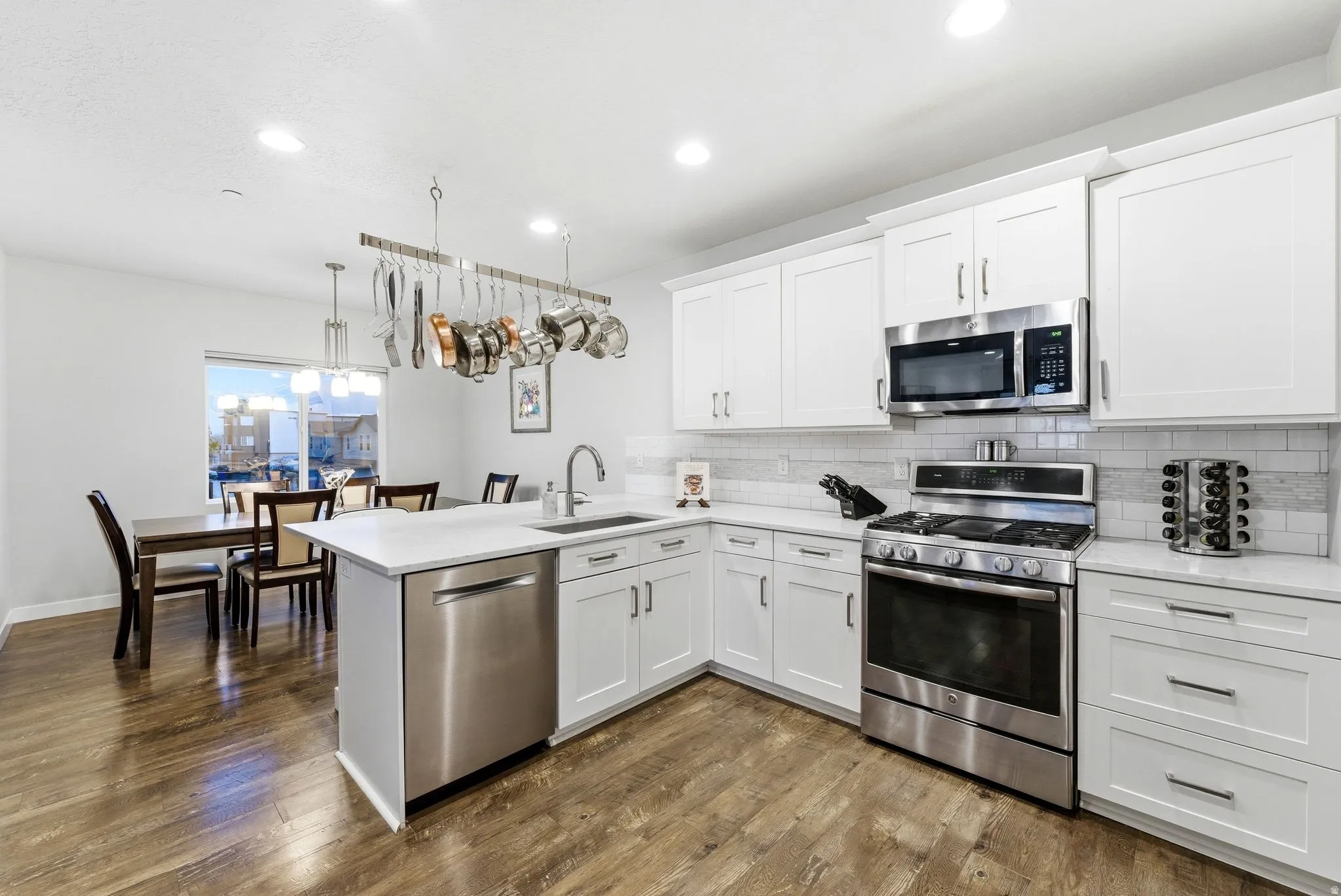 Kitchen featuring stainless steel appliances, white cabinetry, a peninsula, and dark wood-style floors