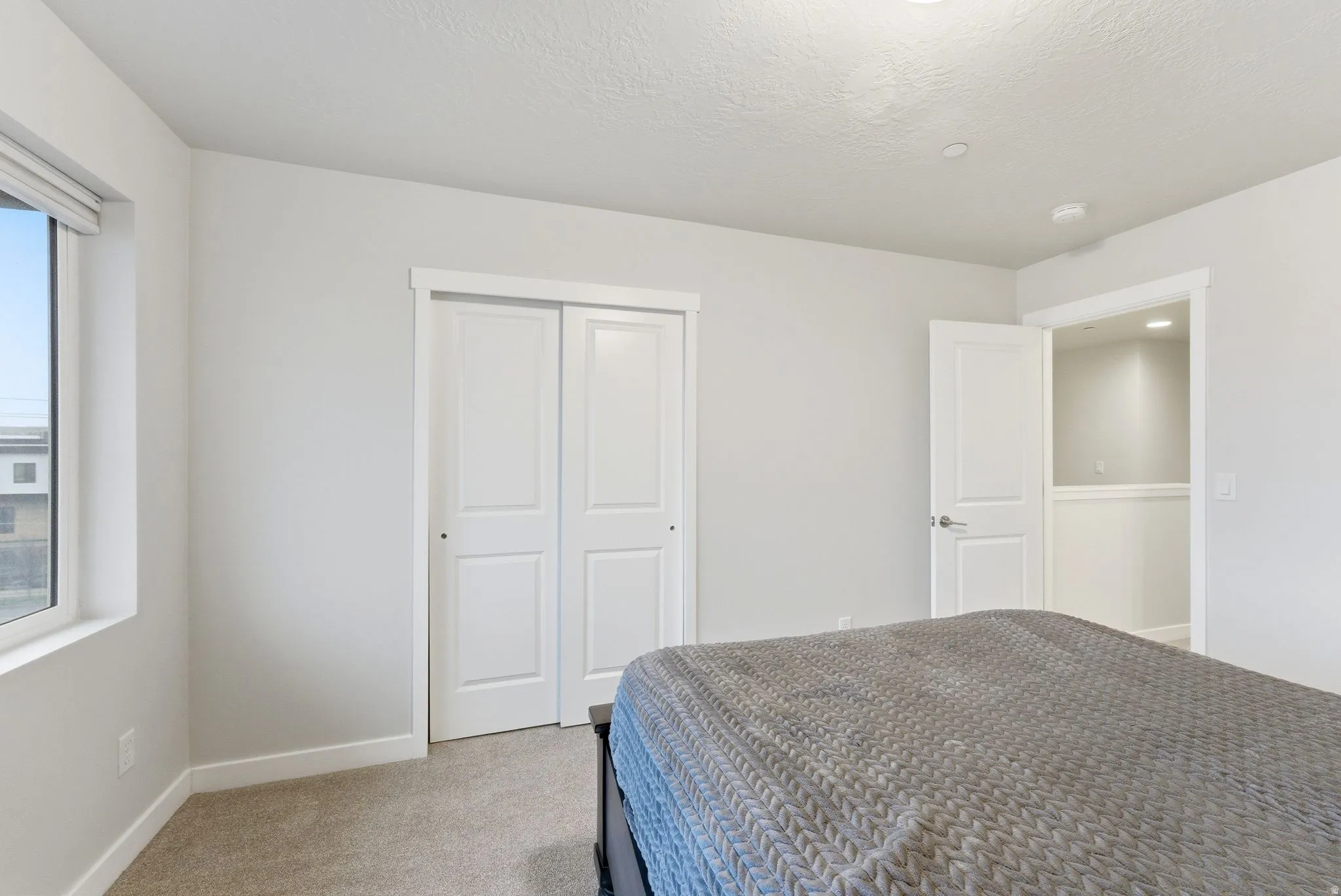 Bedroom featuring light colored carpet, a closet, and a textured ceiling