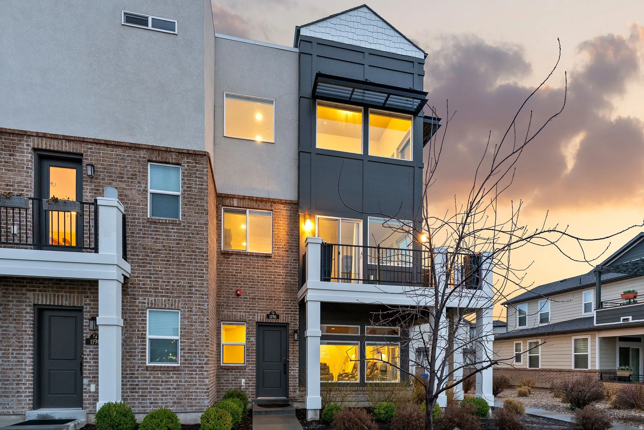 Contemporary home featuring a balcony, stucco siding, and brick siding
